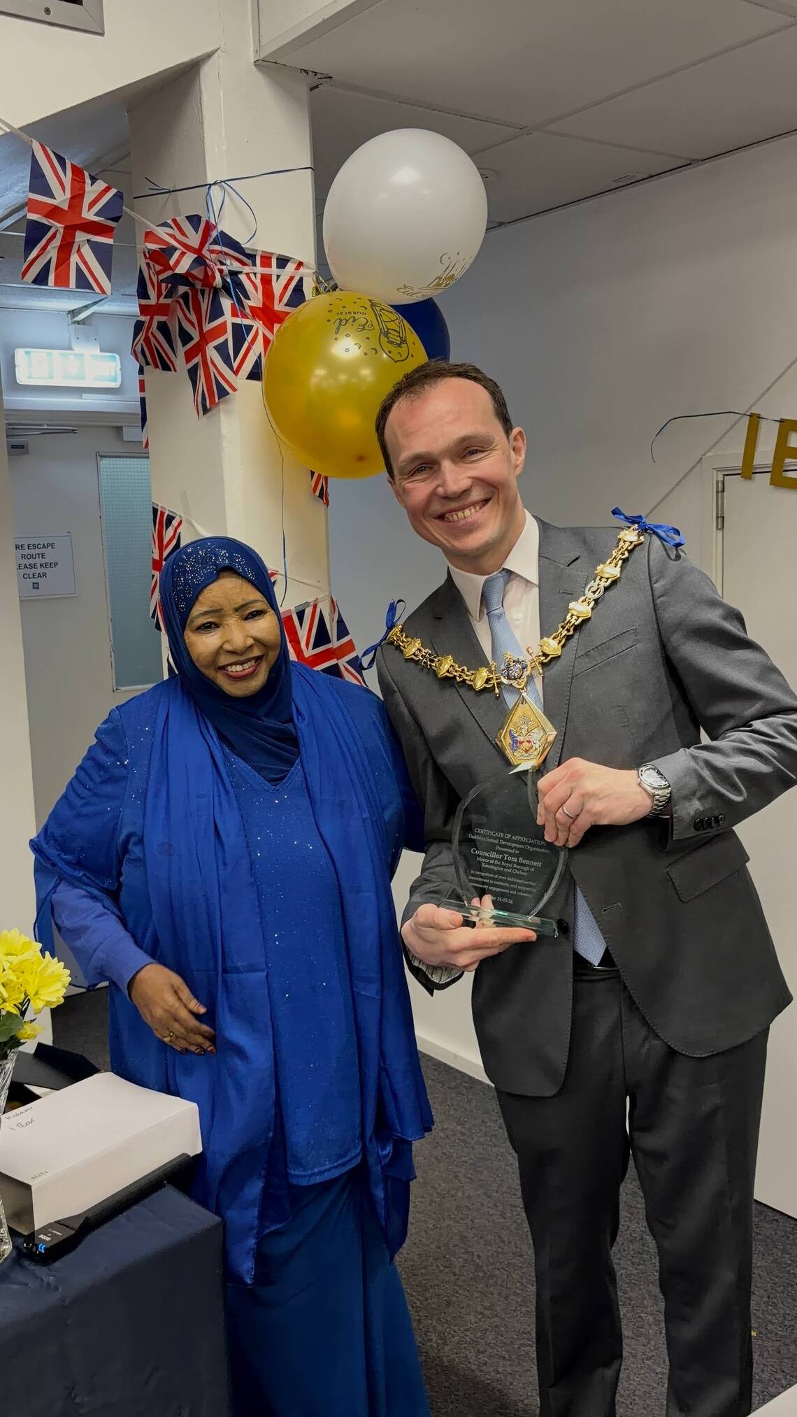 Dahabo Isse, Director of Dadihiye Somali Development Organisation, presents an honorary certificate of appreciation to Mayor Tom Bennett in recognition of his support and engagement with the community.